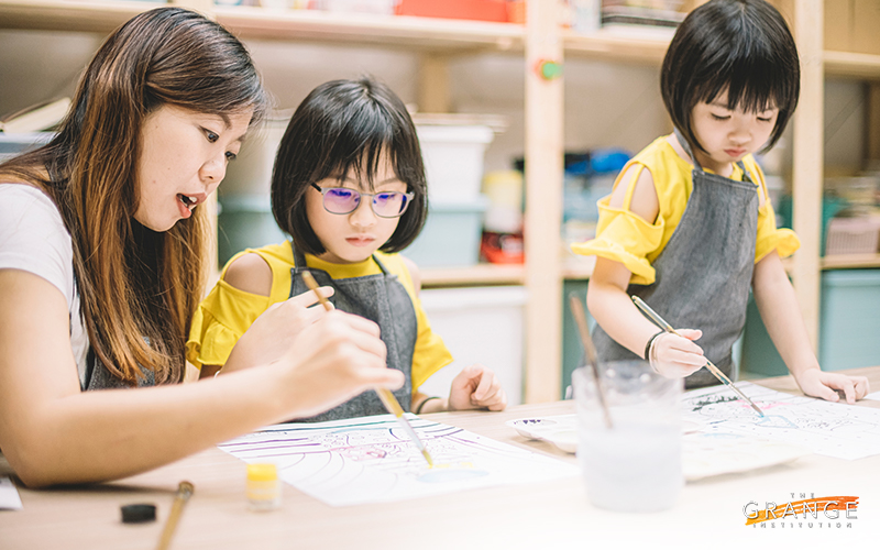 Teacher helping primary school children in art class